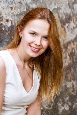 Kızıl saçlı kız dökük bir eski püskü duvara karşı