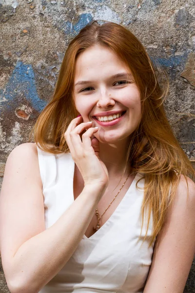 Red-haired girl against the shabby wall of a dilapidated house — Stock Photo, Image