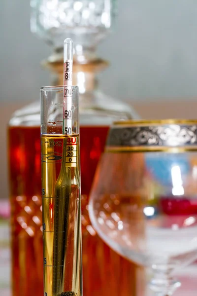 Spirtometer in a test tube against a decanter and a glass