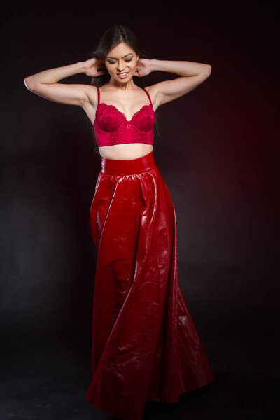 Emotional young girl in a leather skirt and a red lace bra. Studio portrait