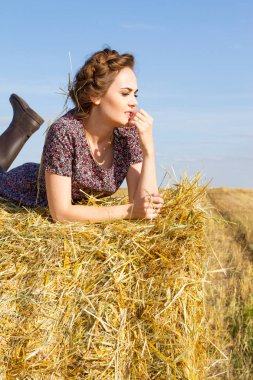 bir saman balya alanda genç köylü kadın yatıyor