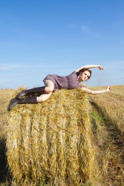 bir saman balya alanda genç köylü kadın yatıyor