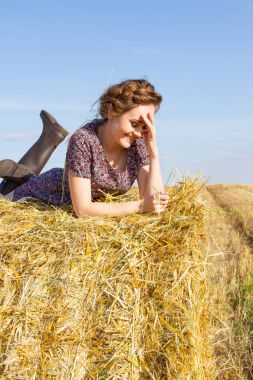 Kız bir saman yığını biçilmiş bir alanın ortasında yatıyor