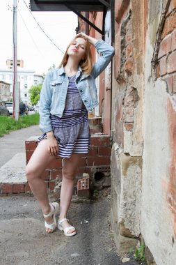 eski bir ev duvar kız kısa bir elbise ve bir kot ceket duruyor