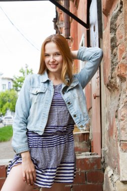 eski bir ev duvar kız kısa bir elbise ve bir kot ceket duruyor