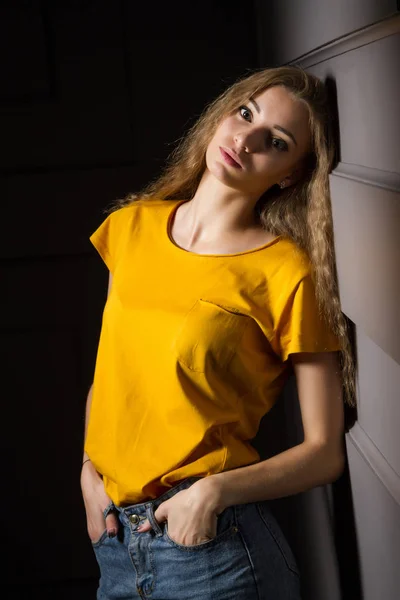 Piękna Młoda Dziewczyna Żółtej Koszulce Dżinsach Stoi Pod Ścianą Ciemnym — Zdjęcie stockowe