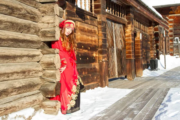 Červenovlasá Dívka Starém Národním Kostýmu Pozadí Dřevěných Domů — Stock fotografie