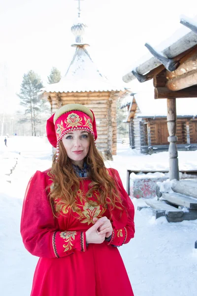 木造住宅を背景にした古い民族衣装の赤髪の少女 — ストック写真