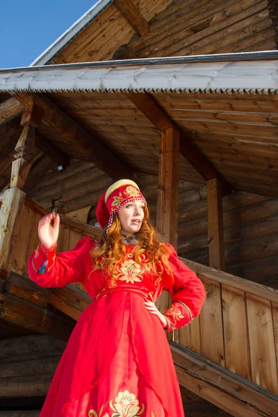 木造住宅を背景にしたロシアの古い民族衣装を着た若い女の子 — ストック写真