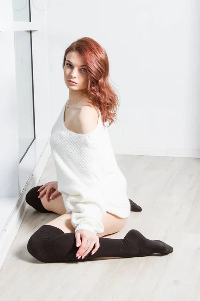 美しい若い女の子が大きな窓の近くの床に座っている — ストック写真