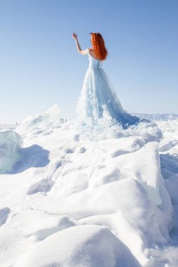 Baykal Gölü 'nün buzları arasında uzun bir gece elbisesi içinde ince bir kız.