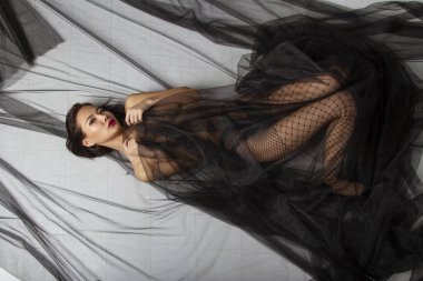 Genç kız çıplak göğüslerini siyah şeffaf bir bezle örtüyor.