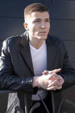 Deri ceketli ve tişörtlü genç adam. Siyah arkaplanda bir portre