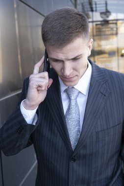 Telefonu olan takım elbiseli genç bir adam. Siyah arkaplanda bir portre