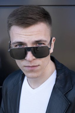 Deri ceketli ve güneş gözlüklü bir adam. Koyu bir arkaplanda portre.