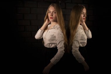 Aynanın yanında, beyaz gömlekli, karanlık bir odada sarışın..