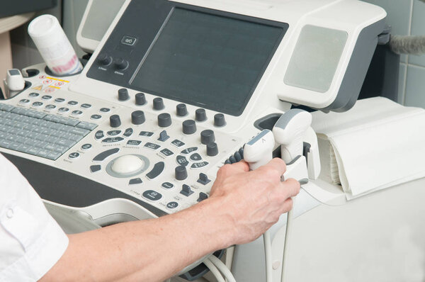 Ultrasound machine close-up with doctor's hand in hospital