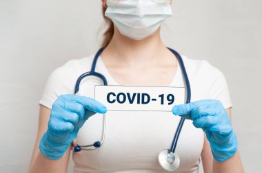 Doktorun elinde Covid-2019 yazılı bir tablet var.