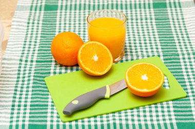 Masada portakal dilimleri ve bıçak var. Bardakta portakal suyu