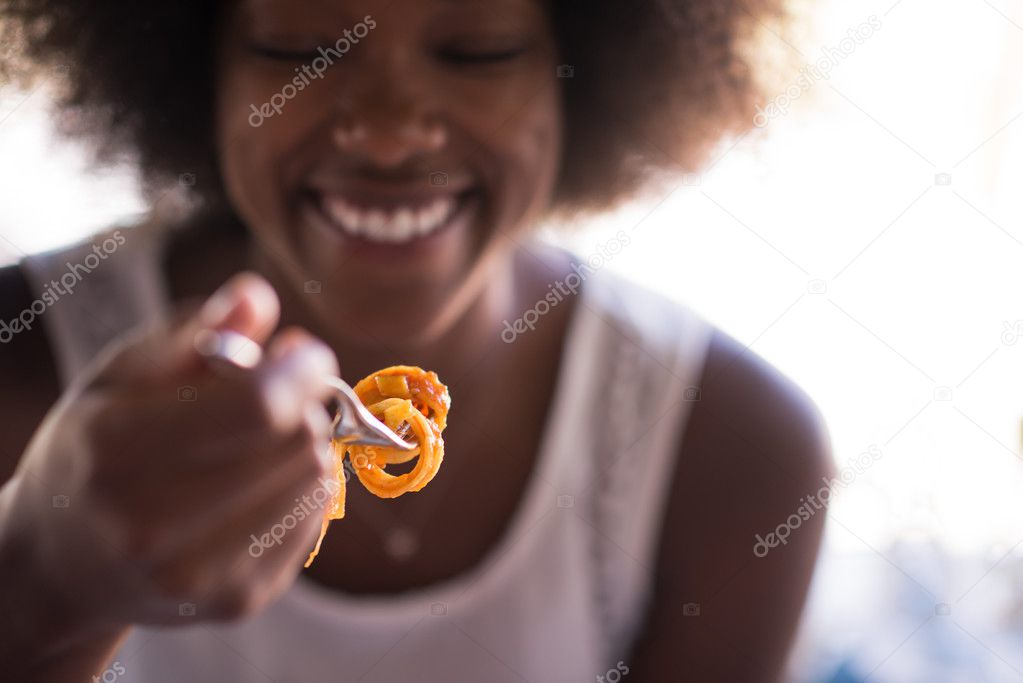 a young African American woman eating pasta