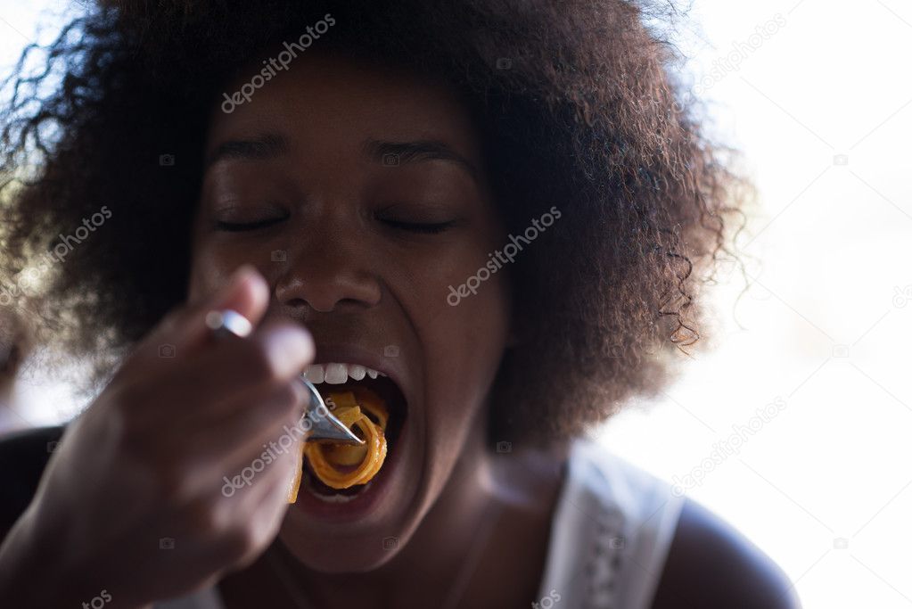 a young African American woman eating pasta