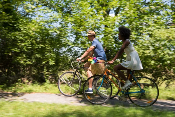 Young multiethnic couple having a bike ride in nature — Stock Photo, Image