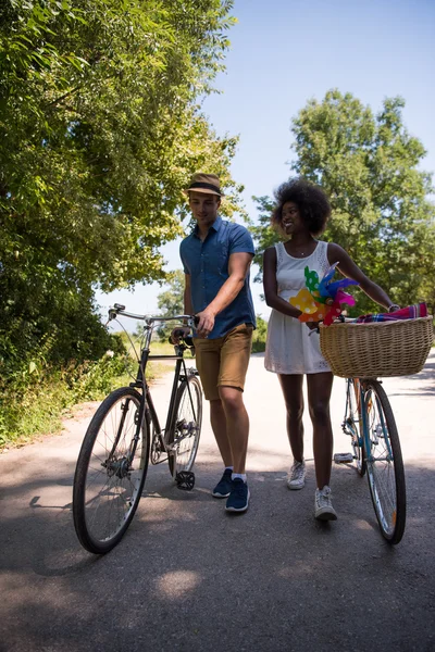 Giovane coppia multietnica che fa un giro in bicicletta nella natura — Foto Stock