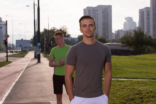 Two young men jogging through the city — Stock Photo, Image