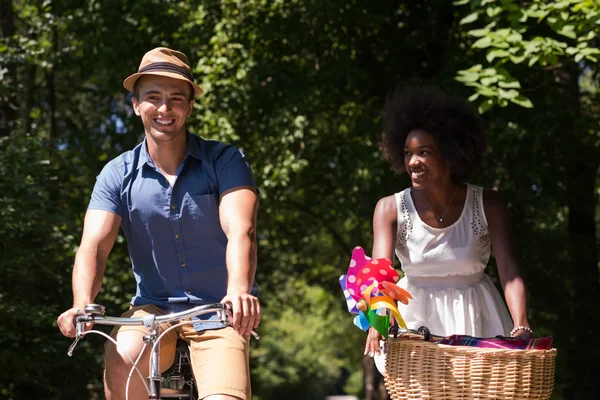 Jovem casal multiétnico ter um passeio de bicicleta na natureza — Fotografia de Stock