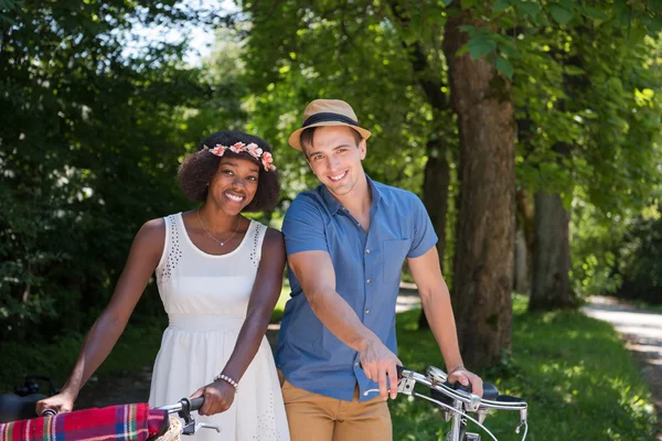 Jovem casal multiétnico ter um passeio de bicicleta na natureza — Fotografia de Stock