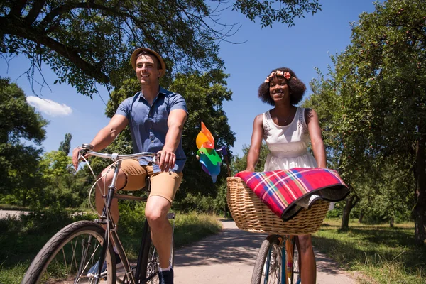 Jovem casal multiétnico ter um passeio de bicicleta na natureza — Fotografia de Stock