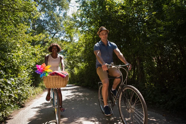 Jovem casal multiétnico ter um passeio de bicicleta na natureza — Fotografia de Stock