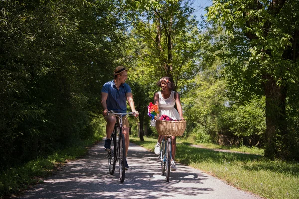 Giovane coppia multietnica che fa un giro in bicicletta nella natura — Foto Stock