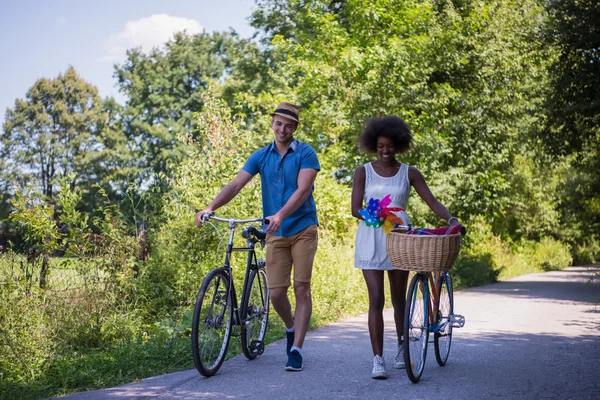 Jovem casal multiétnico ter um passeio de bicicleta na natureza — Fotografia de Stock