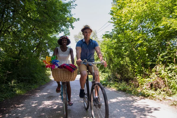 Giovane coppia multietnica che fa un giro in bicicletta nella natura — Foto Stock