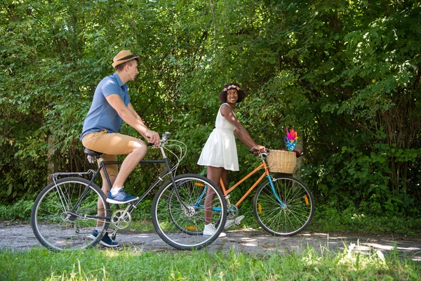 Jovem casal multiétnico ter um passeio de bicicleta na natureza — Fotografia de Stock