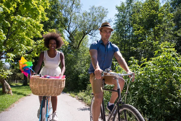 Jovem casal multiétnico ter um passeio de bicicleta na natureza — Fotografia de Stock