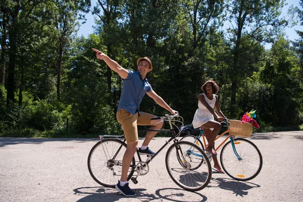 Jovem casal multiétnico ter um passeio de bicicleta na natureza — Fotografia de Stock