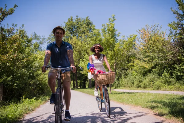 Jovem casal multiétnico ter um passeio de bicicleta na natureza — Fotografia de Stock