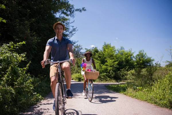 Young multiethnic couple having a bike ride in nature — Stock Photo, Image