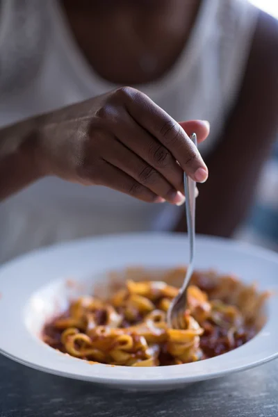 En ung afrikansk amerikansk kvinde, der spiser pasta - Stock-foto