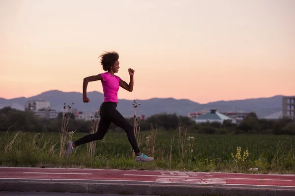 A young African American woman jogging outdoors — Stock Photo, Image