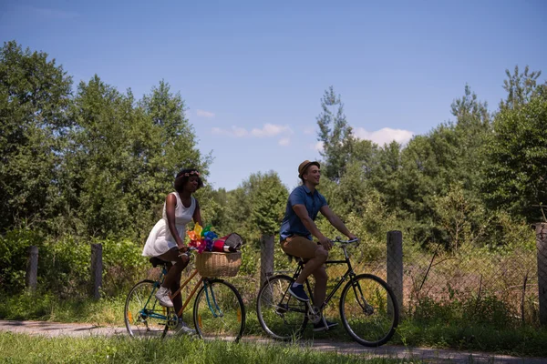 Jovem casal multiétnico ter um passeio de bicicleta na natureza — Fotografia de Stock