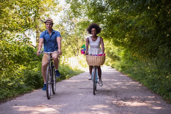 Giovane coppia multietnica che fa un giro in bicicletta nella natura — Foto Stock