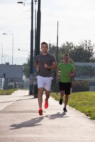 Zwei junge Männer joggen durch die Stadt — Stockfoto