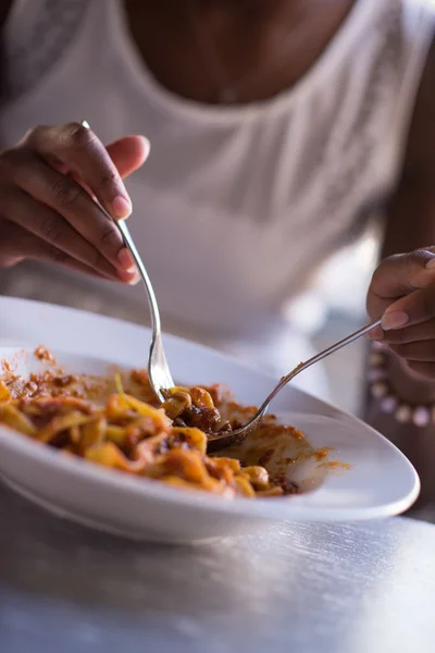 En ung afrikansk amerikansk kvinde, der spiser pasta - Stock-foto