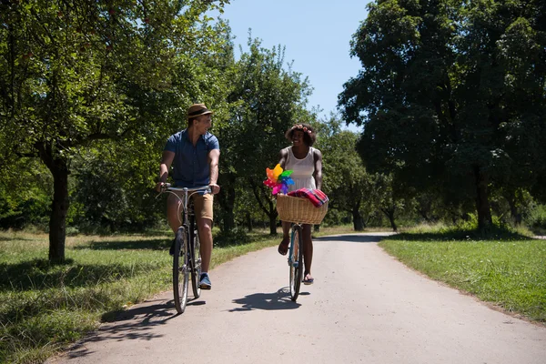 Giovane coppia multietnica che fa un giro in bicicletta nella natura — Foto Stock