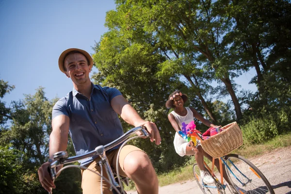 Giovane coppia multietnica che fa un giro in bicicletta nella natura — Foto Stock