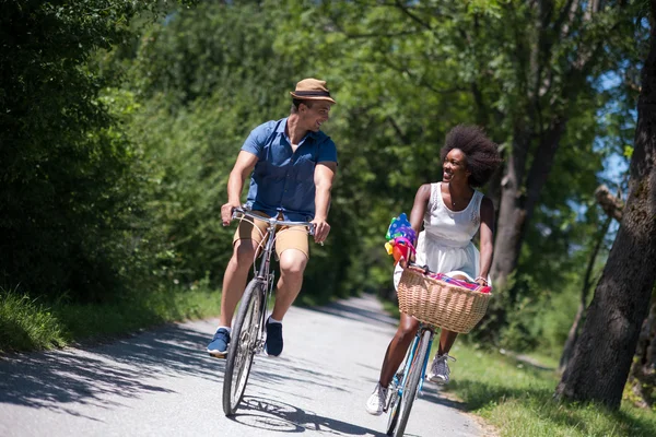 Jovem casal multiétnico ter um passeio de bicicleta na natureza — Fotografia de Stock