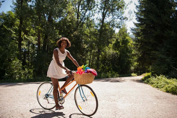 Afro-americana montando uma bicicleta na floresta — Fotografia de Stock